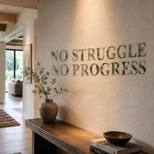 May include: A wooden bench with a vase and a bowl, set against a wall with the text "NO STRUGGLE NO PROGRESS". The letters are textured. The scene is lit by natural light, creating a warm and inviting atmosphere.