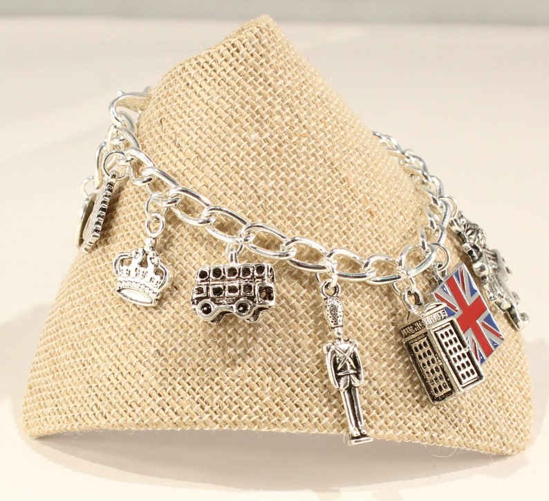 May include: A silver charm bracelet with various London-themed charms, including a crown, a double-decker bus, a telephone booth, a Union Jack flag, and a toy soldier.