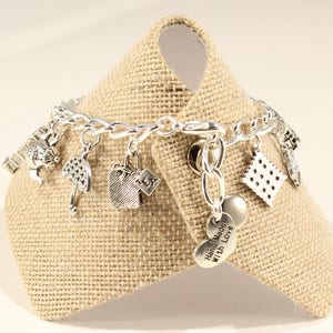 May include: Silver charm bracelet with various charms, including a teapot, umbrella, tea bag, and a heart charm that says "Hand Made with Love".