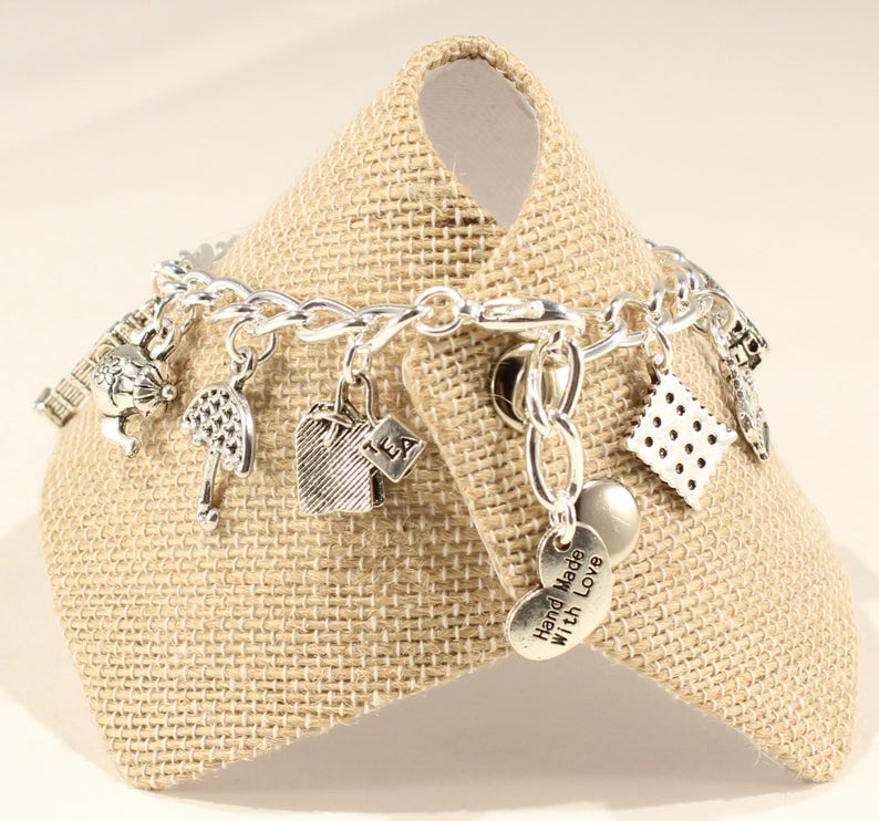 May include: Silver charm bracelet with various charms, including a teapot, umbrella, tea bag, and a heart charm that says "Hand Made with Love".