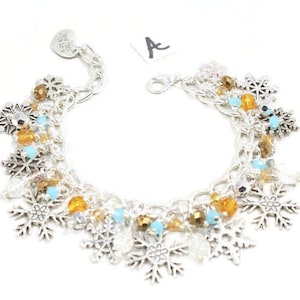 May include: A silver charm bracelet with snowflake charms, blue and amber beads, and a silver heart charm with the text "Find Your Sparkle".