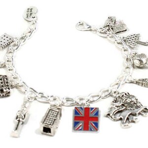 May include: Silver charm bracelet with various London themed charms, including a red, white, and blue Union Jack flag charm, a double-decker bus charm, a crown charm, a telephone booth charm, and a Big Ben charm.
