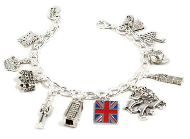 May include: Silver charm bracelet with various London themed charms, including a red, white, and blue Union Jack flag charm, a double-decker bus charm, a crown charm, a telephone booth charm, and a Big Ben charm.