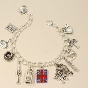 May include: A silver charm bracelet with various charms representing London, England. The charms include a crown, a teacup, a phone booth, a Union Jack flag, a red double-decker bus, a soldier, a lion, and an umbrella.