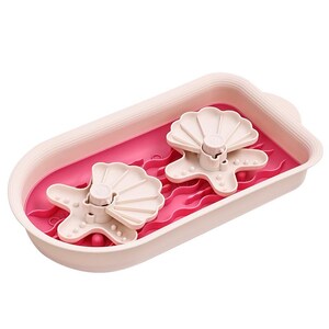 May include: A pink dish drying rack with a bright pink interior. Two white seashell-shaped drying racks are inside. The rack is designed to hold dishes and utensils, providing a convenient space for air drying.