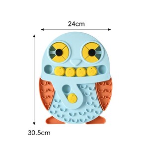 May include: An owl-shaped puzzle toy in blue and orange. The toy measures 24 cm wide and 30.5 cm tall. It has yellow eye and beak details, and several circular compartments with yellow covers. The owl's wings are orange.