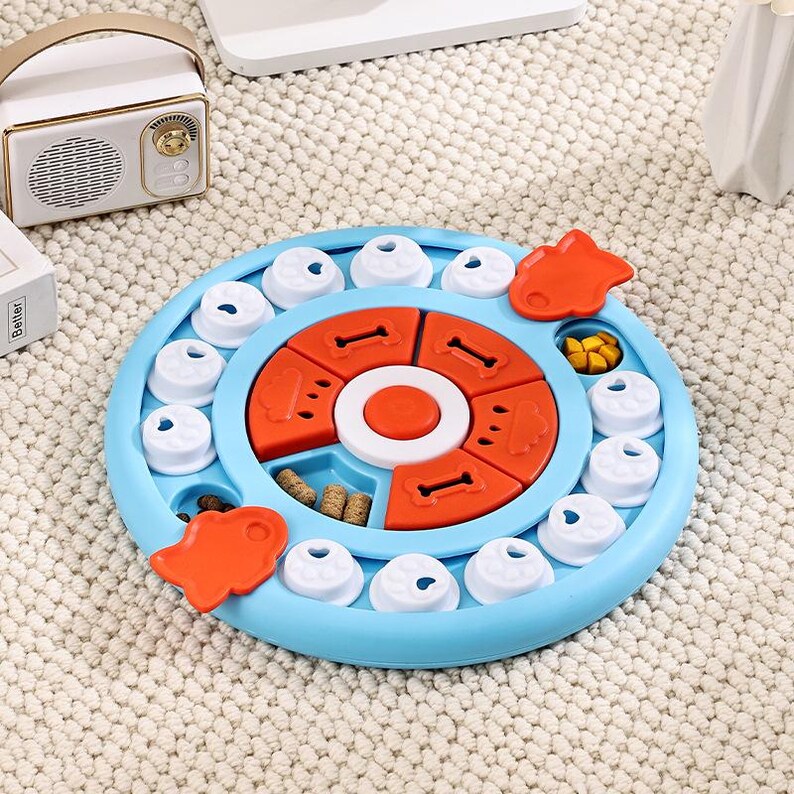 May include: A blue and orange dog puzzle toy with multiple compartments and sliding pieces. The toy features a circular design with various shapes and compartments for treats, promoting mental stimulation for pets.