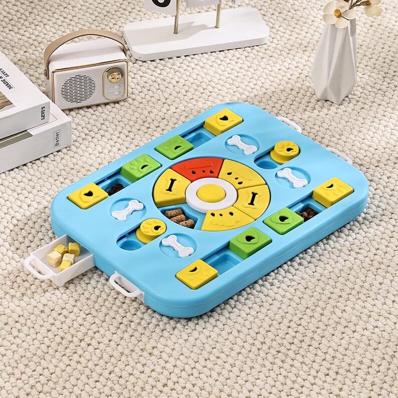 May include: A blue dog puzzle toy with a variety of compartments and sliding drawers. The toy features yellow, green, and red coloured pieces, along with bone-shaped and circular elements. The puzzle is designed to stimulate a dog's mind and provide a fun challenge.