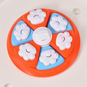 May include: A dog puzzle toy in a circular design with orange, blue, and white components. It has paw-shaped compartments and a central disc. This interactive toy is designed to stimulate a pet's mind.
