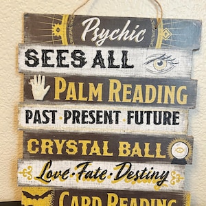 May include: A rectangular wooden wall sign with a jute hanging string, featuring horizontal slats in black, white, and yellow. Text includes Psychic, SEES ALL, PALM READING, PAST PRESENT FUTURE, CRYSTAL BALL, Love-Fate-Destiny, and CARD READING with icons.