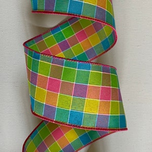 May include: A colorful plaid ribbon with a pink, green, yellow, blue, and purple checkered pattern. The ribbon has a pink edge.