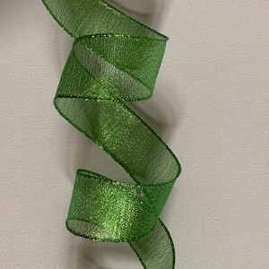 May include: A vibrant green ribbon with a shimmering, metallic finish. The ribbon is loosely curled, creating a flowing, decorative effect. The material has a mesh-like texture, adding depth and visual interest. Ideal for crafts and gift wrapping.