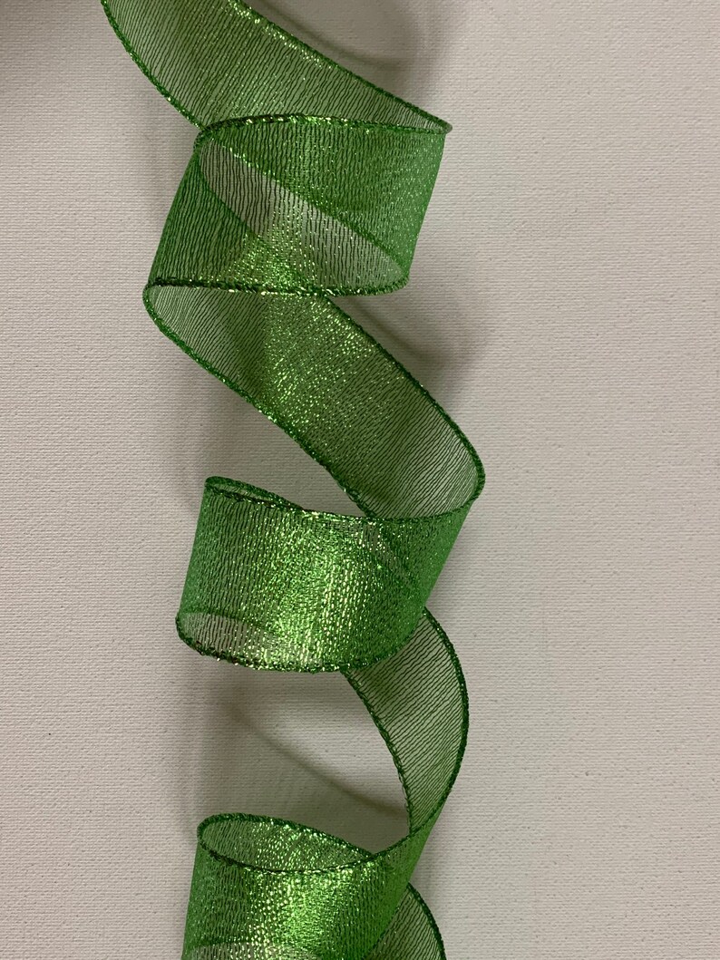 May include: A vibrant green ribbon with a shimmering, metallic finish. The ribbon is loosely curled, creating a flowing, decorative effect. The material has a mesh-like texture, adding depth and visual interest. Ideal for crafts and gift wrapping.