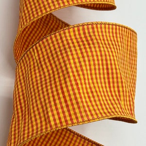 May include: A yellow and red gingham ribbon with a wired edge. The ribbon is folded and curled, showing the pattern and texture.