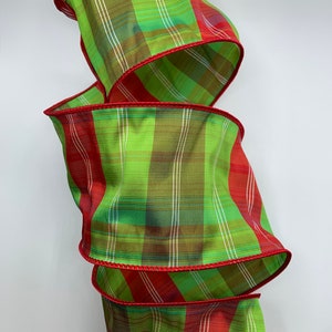 May include: Green and red plaid ribbon with a red wired edge. The ribbon is folded into a spiral shape.