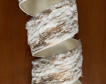 May include: White and gold faux fur ribbon with a distressed woodgrain pattern. The ribbon is curled and ready to be used for crafting or decorating.
