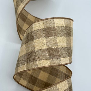 May include: A roll of brown and beige gingham ribbon with a wired edge. The ribbon is made of a textured fabric and has a subtle sheen.