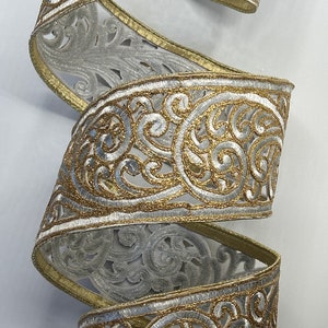 May include: Gold and silver ribbon with a delicate, intricate floral pattern. The ribbon is woven with a sheer, translucent fabric and features a raised, embroidered design.