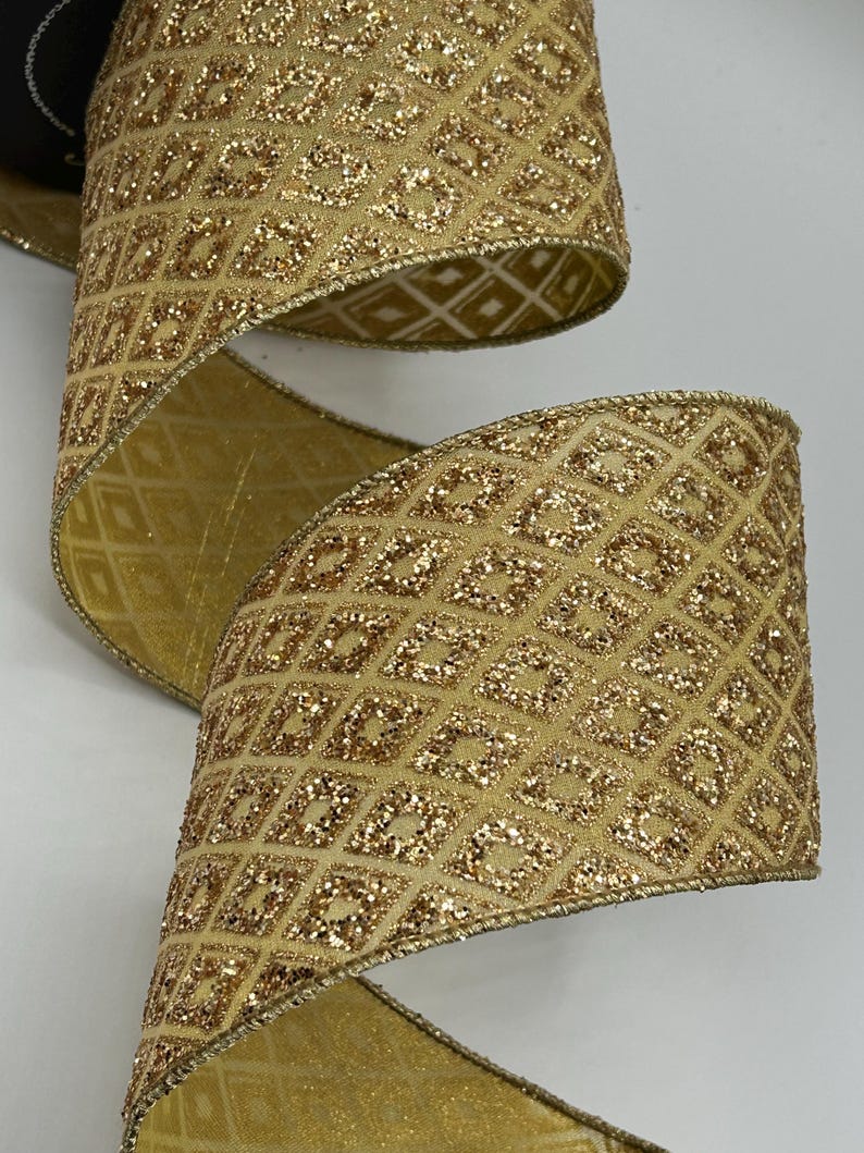 Puede incluir: Primer plano de una cinta dorada con un patr&oacute;n de diamantes y detalles brillantes. La cinta est&aacute; enrollada, revelando ambos lados del material. Los bordes est&aacute;n adornados con un borde dorado. Esta cinta decorativa es adecuada para manualidades y envolver regalos.