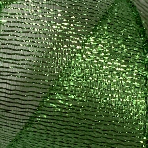 May include: Close-up of a shimmering green mesh ribbon. The ribbon has a textured, woven appearance with horizontal lines and a metallic sheen. The material reflects light, creating a sparkling effect, suitable for crafts and decorations.