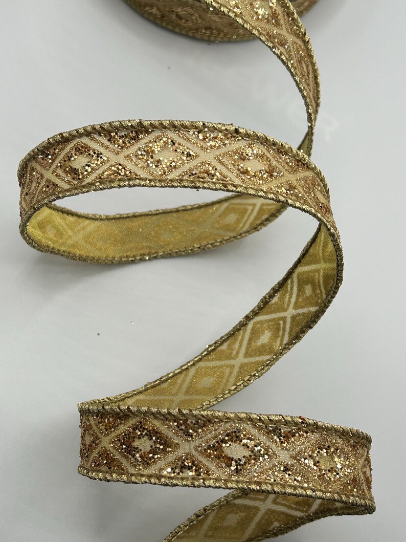 Puede incluir: Cinta dorada con un patr&oacute;n de diamantes y detalles brillantes. La cinta est&aacute; enrollada, mostrando su dise&ntilde;o y textura. Los bordes est&aacute;n adornados con un detalle dorado en forma de cuerda. Adecuada para manualidades y envolver regalos.