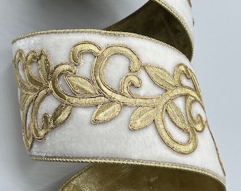 Op de afbeelding: Wit fluwelen lint met gouden geborduurde bloemenmotieven. Het lint heeft gouden randen en is spiraalvormig gewikkeld. Geschikt voor knutselen, cadeauverpakking of feestdecoratie. De lintbreedte is ongeveer 2.5 cm.