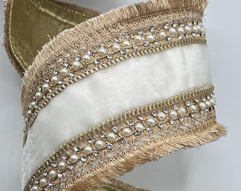 May include: A decorative ribbon with a white center and gold edges. The ribbon is embellished with faux pearls and clear rhinestones along the edges. The ribbon has a soft, velvety texture and a fringed trim.