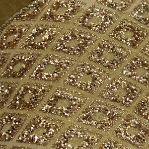 Puede incluir: Primer plano de una cinta dorada con un patr&oacute;n de diamantes. Los diamantes est&aacute;n llenos de purpurina dorada, creando un efecto brillante. La cinta tiene un aspecto texturizado y probablemente se utiliza para decoraci&oacute;n o manualidades.