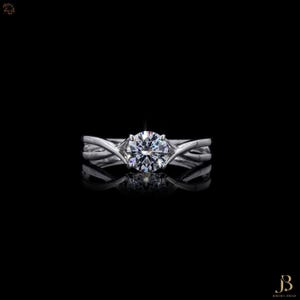 May include: A silver-toned ring featuring a single round brilliant-cut clear gemstone held in a six-prong setting. The band is composed of two intertwining metal strands that meet at the center to support the central stone, creating a reflective surface.