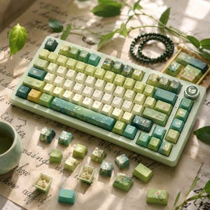 May include: A mechanical keyboard with a light green frame and a gradient of cream to green keycaps. The keycaps feature botanical illustrations of leaves and flowers. A circular knob with a leaf icon is on the right side, and extra loose keycaps are scattered nearby.
