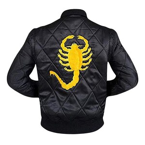 May include: A black quilted bomber jacket featuring a large, embroidered yellow scorpion design on the back. The jacket has a ribbed collar, cuffs, and hem, with a diamond-patterned stitched texture throughout the outer shell fabric.