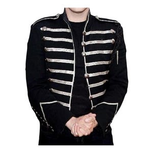 May include: A black military-style jacket featuring a high collar, long sleeves, and a front closure with silver-toned buttons. The garment is decorated with horizontal silver braided cord trim across the chest and cuffs, creating a structured look.