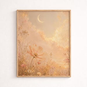Op de afbeelding: Een ingelijste kunstdruk met een dromerig landschap met een grote perzikroze bloem op de voorgrond. Het kunstwerk heeft een zacht, pastelkleurig kleurenpalet met een halve maan in de lucht en een veld met wilde bloemen.