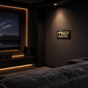 Może przedstawiać: Pok&oacute;j kina domowego z dużym ekranem wyświetlającym scenę nocnego nieba. Pok&oacute;j posiada znak Dolby Atmos, głośniki i ciemnoszarą sofę. Ciepłe oświetlenie podkreśla ekran i cechy pokoju.