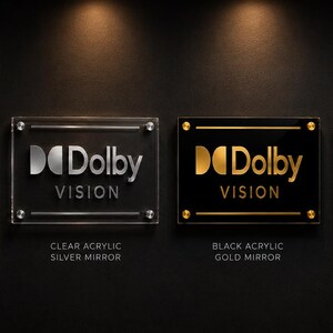 K&ouml;nnte beinhalten: Vier rechteckige Acrylschilder mit dem Dolby Vision Logo und Schriftzug. Zwei Schilder bestehen aus klarem Acryl mit goldener oder silberner Spiegelschrift, zwei aus schwarzem Acryl mit goldener oder silberner Spiegelschrift, montiert mit Metall.