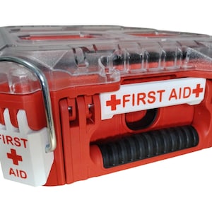 Puede incluir: Un maletín de primeros auxilios de plástico rojo y blanco con tapa transparente. Incluye un asa negra, cierres metálicos y etiquetas blancas en el frente y el lateral con el texto FIRST AID y un símbolo de cruz roja en las piezas.