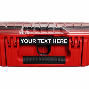 May include: A red plastic storage case with a clear lid and black latches. The front features a black rectangular nameplate with the white text YOUR TEXT HERE centered above a black handle and a circular opening for a lock or security seal.