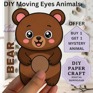 Puede incluir: Un oso de papel con grandes ojos negros, mejillas rosadas y una barriga marrón claro. El texto dice: DIY Moving Eyes Animals, BEAR, OFFER BUY 1 GET 1 MYSTERY ANIMAL, DIY PAPER CRAFT DIGITAL DOWNLOAD y Softbyte PLANNER.