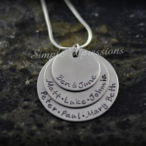 May include: Silver necklace with multiple layered circles, each engraved with names: Ben & June, Matt, Luke, John, Peter, Paul, Mary, Beth.