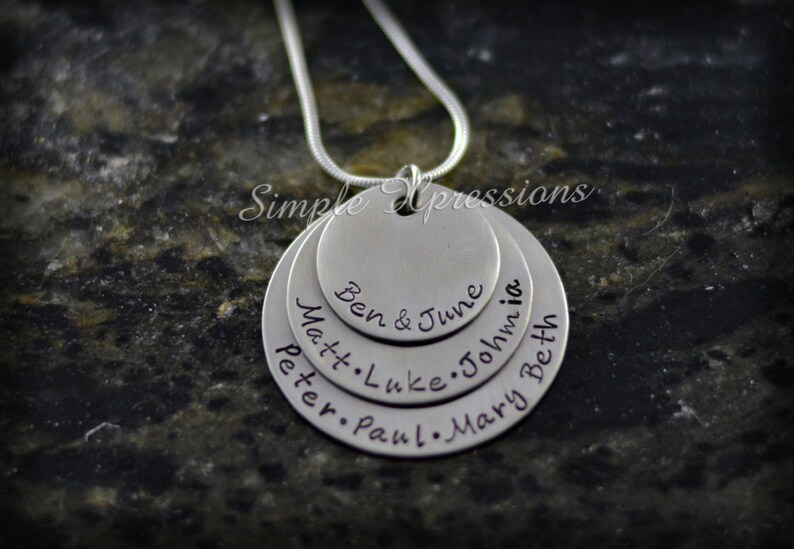 May include: Silver necklace with multiple layered circles, each engraved with names: Ben & June, Matt, Luke, John, Peter, Paul, Mary, Beth.