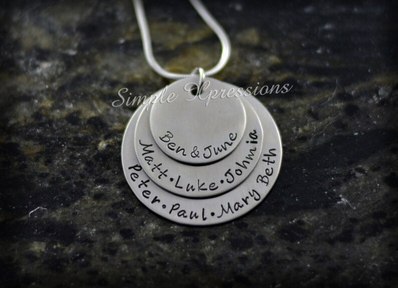 May include: Silver necklace with multiple circular pendants, each engraved with names. The names on the pendants are "Peter", "Paul", "Mary", "Matt", "Luke", "John", "Beth", and "Ben & June".