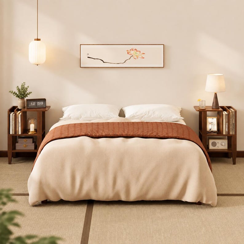 May include: A bedroom set featuring a bed with a cream-colored duvet and a rust-colored runner, flanked by two dark wood nightstands with open shelving. Above the bed hangs a horizontal framed print of a lotus flower and a white pendant light.