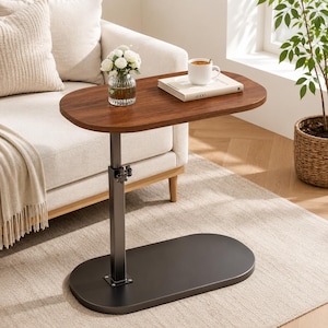 May include: A C-shaped side table with a dark brown oval wooden top and a black metal base. The table features a central vertical support column with an adjustable height mechanism controlled by a black knob, resting on a flat oval base.