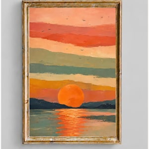 Pode incluir: Uma pintura emoldurada retratando um pôr do sol sobre um corpo de água com montanhas escuras ao fundo. O céu apresenta faixas horizontais de laranja, rosa e verde suave, com um grande sol laranja refletindo na água e pequenos pássaros.