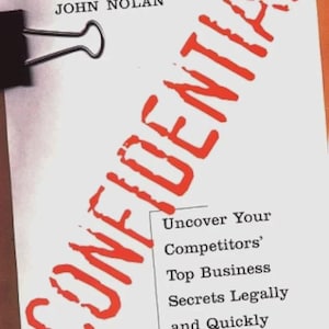 May include: A white paper with the name "JOHN NOLAN" at the top and the word "CONFIDENTIAL" in large red letters diagonally across the page. The text below reads "Uncover Your Competitors' Top Business Secrets Legally and Quickly - and Protect Your Own."