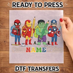 May include: A DTF transfer sheet featuring cartoon illustrations of Spider-Man, Iron Man, Hulk, and Captain America carrying school supplies like pencils and books. The text READY TO PRESS appears at the top, and the word NAME is at the bottom.
