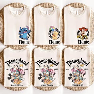 Puede incluir: Seis camisetas blanquecinas con gr&aacute;ficos de personajes de Disney. La fila superior presenta a Stitch, Winnie the Pooh y Woody. La fila inferior muestra gr&aacute;ficos de Disneyland con varios personajes de Disney. Cada camiseta tiene la palabra "Name" o "Disneyland".