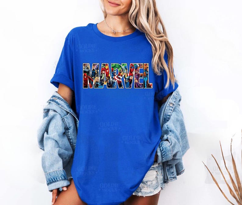 Peut inclure: Un t-shirt bleu roi &agrave; manches courtes avec le mot MARVEL imprim&eacute; en grandes lettres majuscules sur la poitrine. Les lettres sont remplies d'un collage color&eacute; repr&eacute;sentant diverses illustrations de personnages de bandes dessin&eacute;es Marvel.