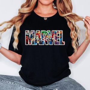 Peut inclure: Un t-shirt noir &agrave; manches courtes avec le mot MARVEL &eacute;crit en grandes lettres blanches. &Agrave; l'int&eacute;rieur de chaque lettre se trouve une illustration graphique color&eacute;e de divers personnages de bandes dessin&eacute;es, dont Iron Man, Hulk, Thor et Captain America.