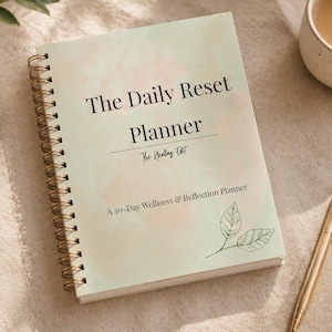 May include: A spiral-bound planner with a pale green watercolor cover. The text reads The Daily Reset Planner, The Healing Edit, and A 30-Day Wellness & Reflection Planner. A small line drawing of two leaves is printed in the bottom right corner.